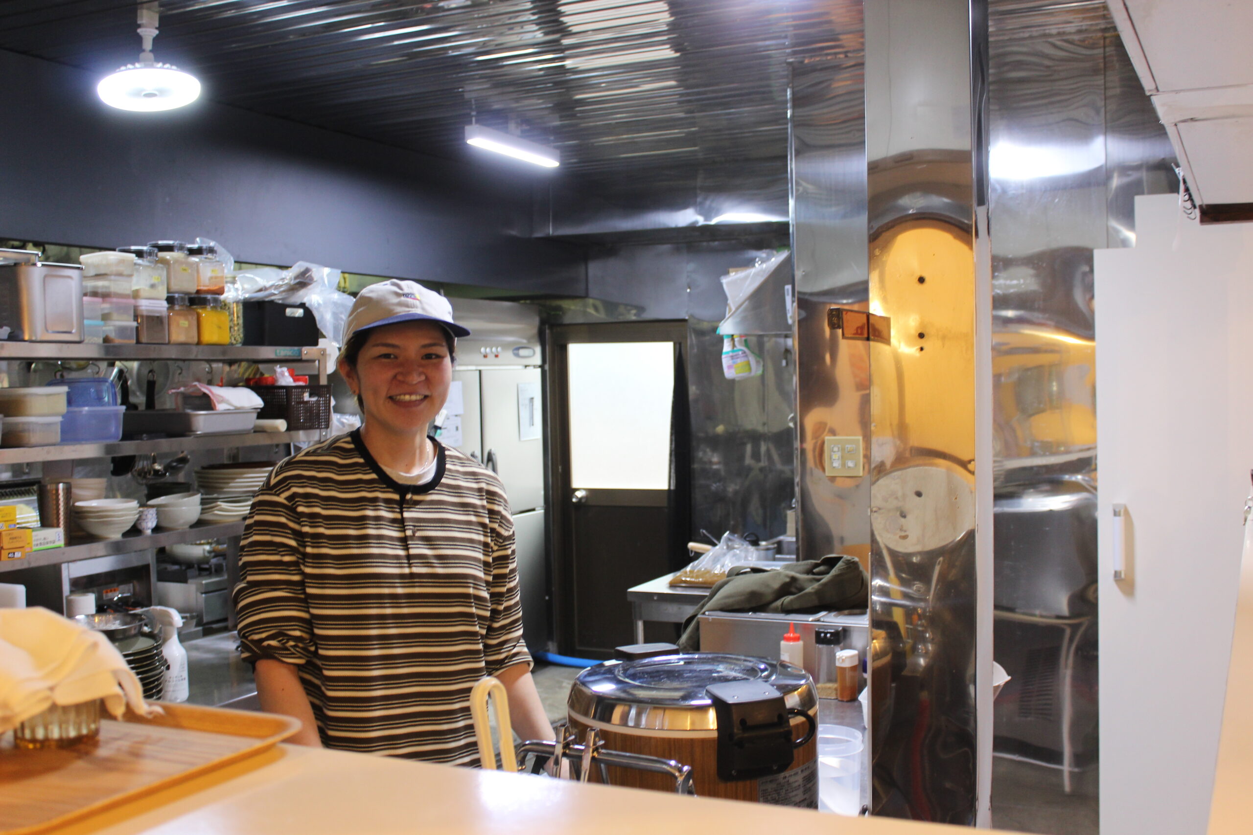 TAMCURRY ｜ タムカレー　田村ゆかり氏。カウンター越しで厨房に立ち、笑顔で。