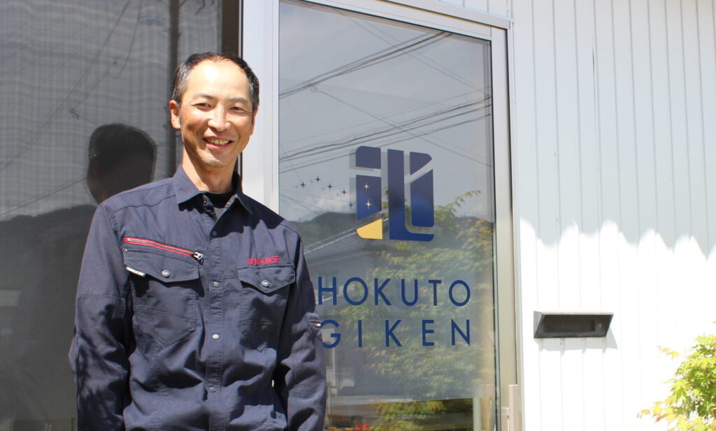 有限会社北斗技研 金子雄三さん。社屋玄関にて。