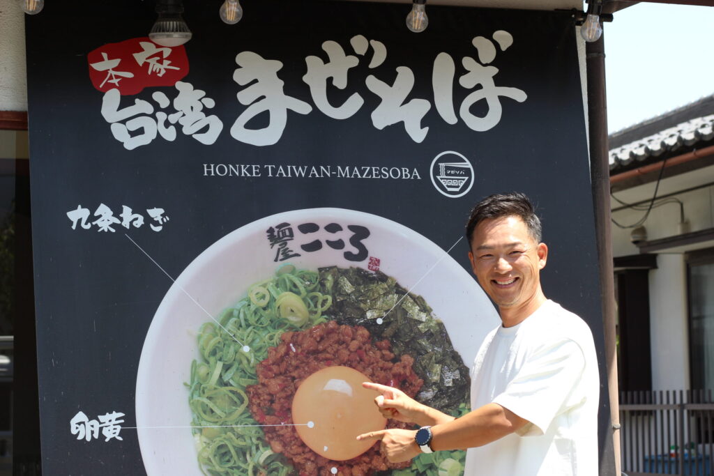株式会社こころ｜麺屋こころ 石川琢磨さん。長野店、店舗前で笑顔。