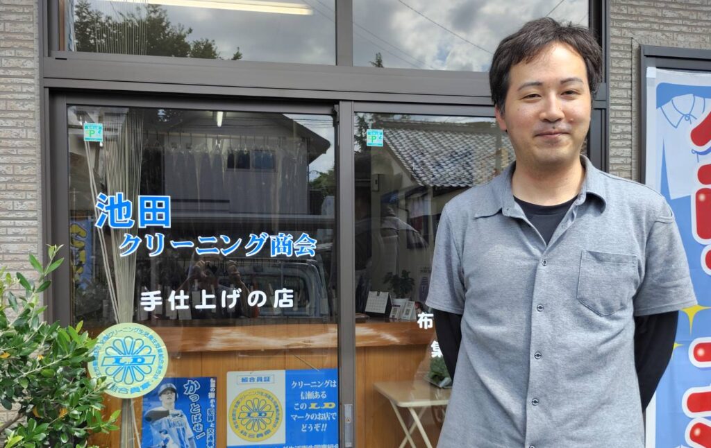 池田クリーニング商会の池田拓真さん。店舗前にて。